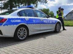policjantka ruchu drogowego przy oznakowanym radiowozie, w dłoniach trzyma laserowy miernik prędkości