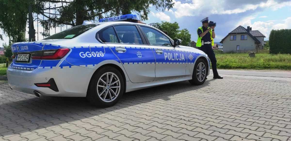 bezpieczne święta wielkanocne - nowosądecka Policja zapowiada wzmożone działania. Na zdjęciu policjantka ruchu drogowego przy oznakowanym radiowozie, w dłoniach trzyma laserowy miernik prędkości