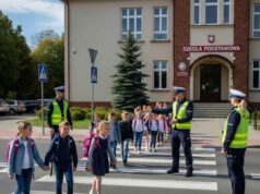 przejście dla pieszych pod szkołą, na nim dzieci i obok policjanci. Wygenerowane przez AI Google Imagen-4