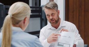 Bramont - bramy, okna, drzwi. mężczyzna w białej koszuli wskazuje na dokument trzymany w ręku