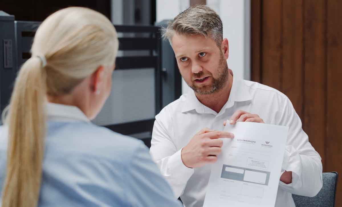 Bramont - bramy, okna, drzwi. mężczyzna w białej koszuli wskazuje na dokument trzymany w ręku