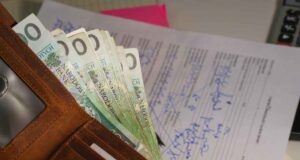 nadpłata podatku od nieruchomości - jak odzyskać. portfel, banknoty, w tle dokumenty