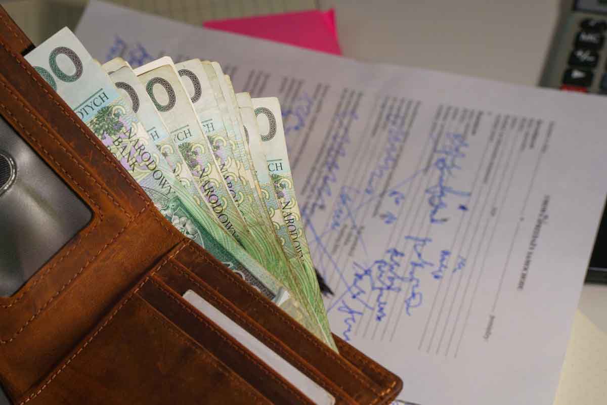 nadpłata podatku od nieruchomości - jak odzyskać. portfel, banknoty, w tle dokumenty